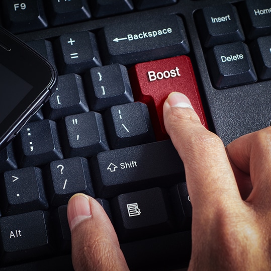 computer keyboard closeup with red enter button with "BOOST" label symbolizing the decision to boost business growth